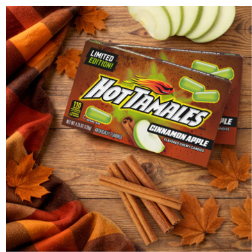 Hot Tamales Cinnamon Apple candy packaging on a wooden surface with autumn leaves and cinnamon sticks.