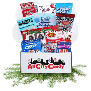 Curated box of Winter theme candy in colorful box sitting on pine bough